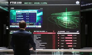 A City worker watches a stock ticker screen in the London stock-exchange